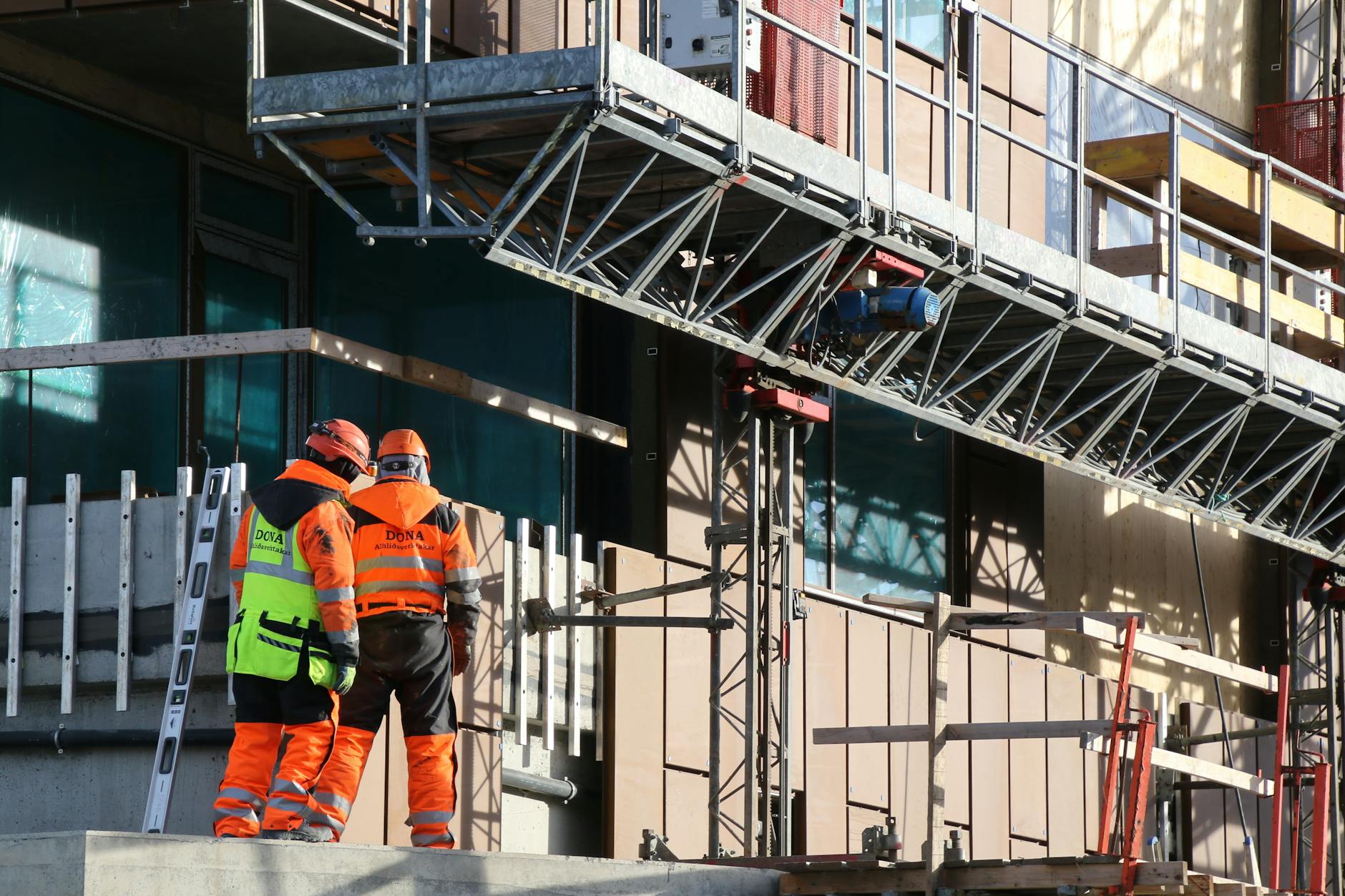 two construction workers standing on scaffolding